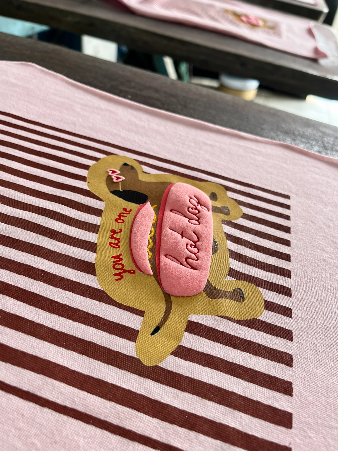 Estampa de cachorro-quente com efeito puff rosa em relevo sobre tecido listrado
