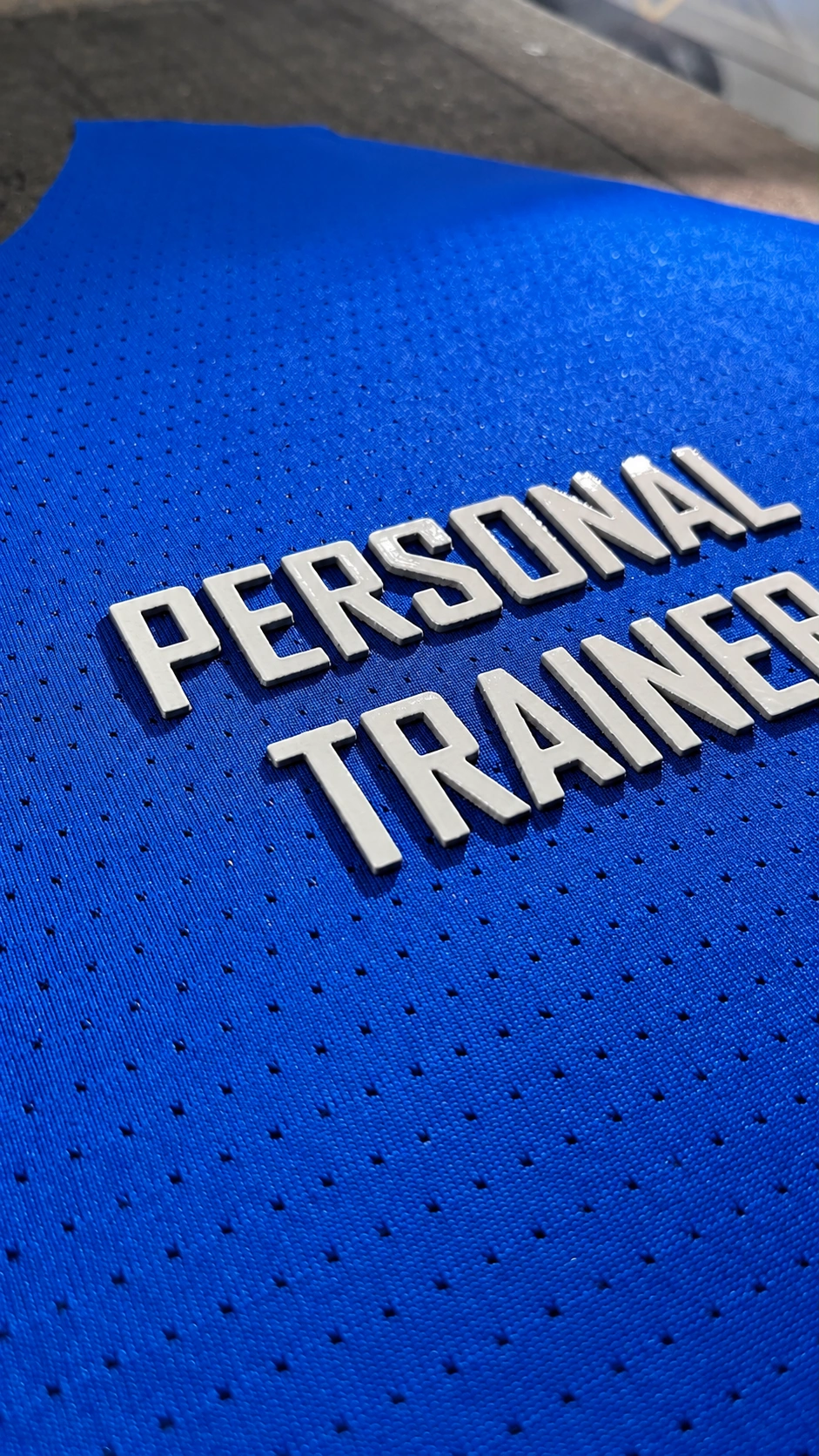 Letras brancas PERSONAL TRAINER em relevo 3D sobre tecido azul